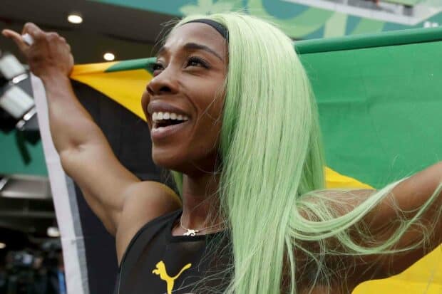Shelly Ann Fraser Pryce smiles joyfully holding the Jamaican flag behind her, 2K Desktop Wallpaper