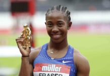 Shelly Ann Fraser Pryce smiles while holding a golden trophy at a track event, 2K Desktop Wallpaper
