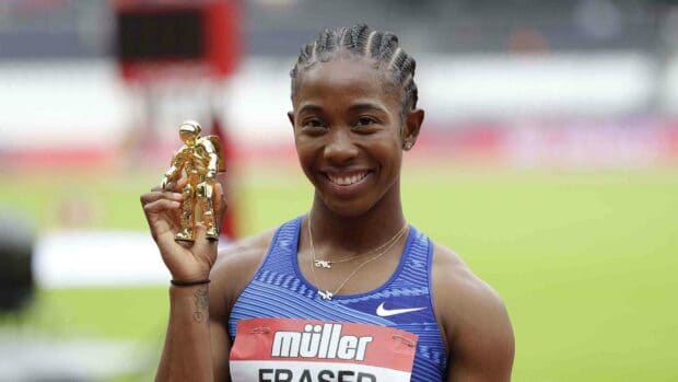 Shelly Ann Fraser Pryce smiles while holding a golden trophy at a track event, 2K Desktop Wallpaper