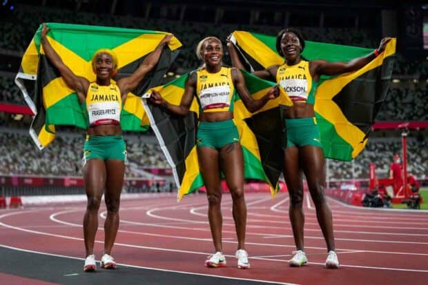 Shelly Ann Fraser Pryce and her Jamaican teammates hold their national flags after a race on the track, HD Desktop Wallpaper