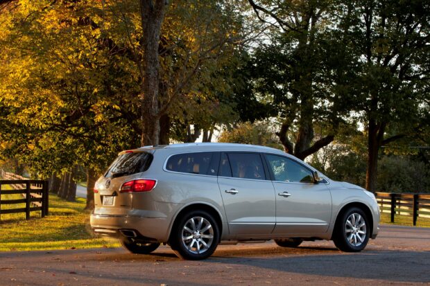 A silver Buick Enclave is parked on a road near trees with yellow autumn leaves in the evening light, 2K Desktop Wallpaper