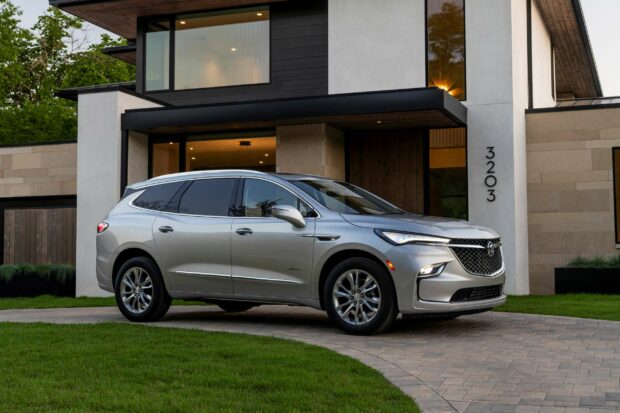 A silver Buick Enclave is parked on a driveway beside a modern house with large glass windows, 2K Desktop Wallpaper