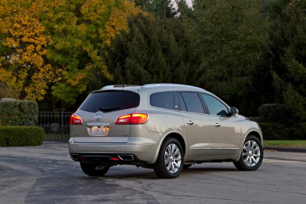 A silver Buick Enclave is parked on a paved road with autumn trees in the background, 2K Desktop Wallpaper