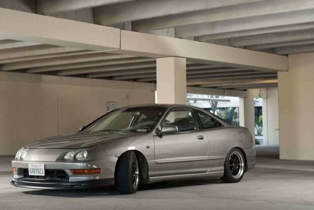 A silver Honda Integra is parked inside a concrete parking structure with natural light illuminating the car, HD Desktop Wallpaper