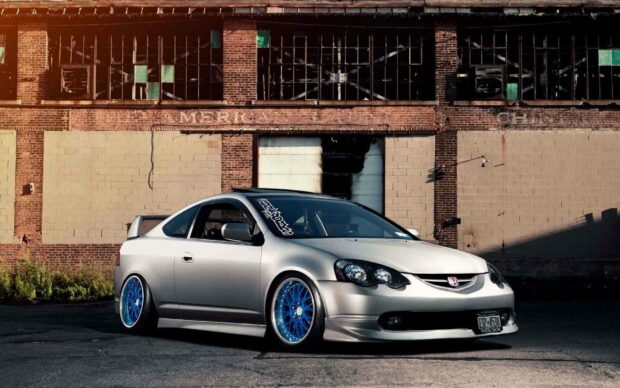 A silver Honda Integra with custom blue rims parked in front of an old brick building during sunset, HD Desktop Wallpaper