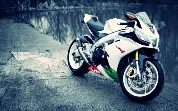 A white Aprilia motorcycle is parked on a cracked road with reflective water nearby, HD Desktop Wallpaper