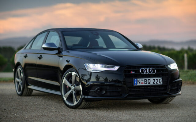 Sleek Black Audi S6 Sedan With LED Headlights On Sunset Road Wallpaper