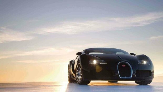 A sleek black Bugatti Veyron is parked on a flat surface with the sunset sky in the background, HD Desktop Wallpaper