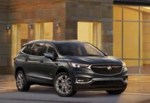 The Buick Enclave is parked in an elegant urban setting with warm lighting on the building, 4K Desktop Wallpaper