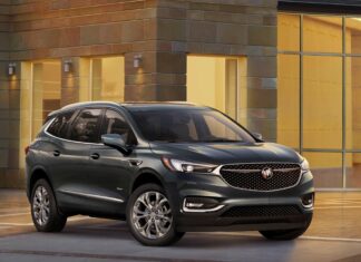 The Buick Enclave is parked in an elegant urban setting with warm lighting on the building, 4K Desktop Wallpaper