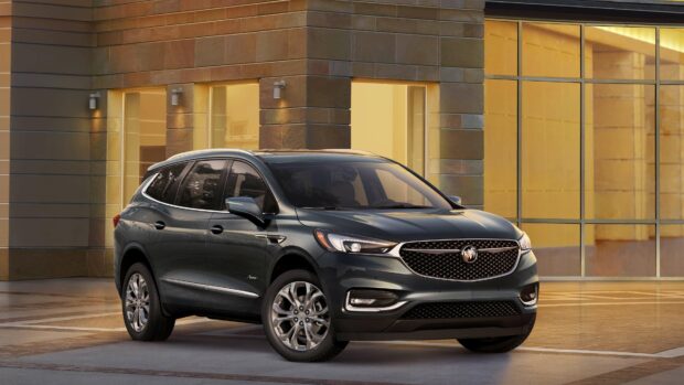 The Buick Enclave is parked in an elegant urban setting with warm lighting on the building, 4K Desktop Wallpaper