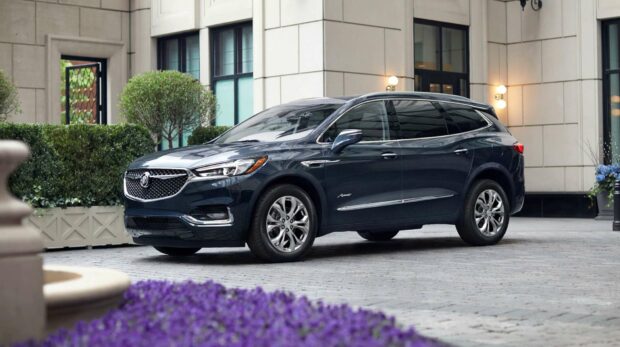 A sleek Buick Enclave is parked in front of a building with greenery and flowers around it, HD Desktop Wallpaper