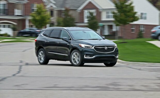 A Buick Enclave is driving smoothly through a residential neighborhood with houses in the background, HD Desktop Wallpaper