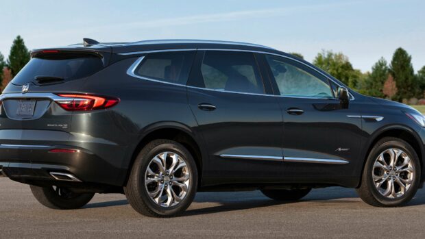 A sleek black Buick Enclave is parked on a paved surface with trees in the background, 4K Desktop Wallpaper
