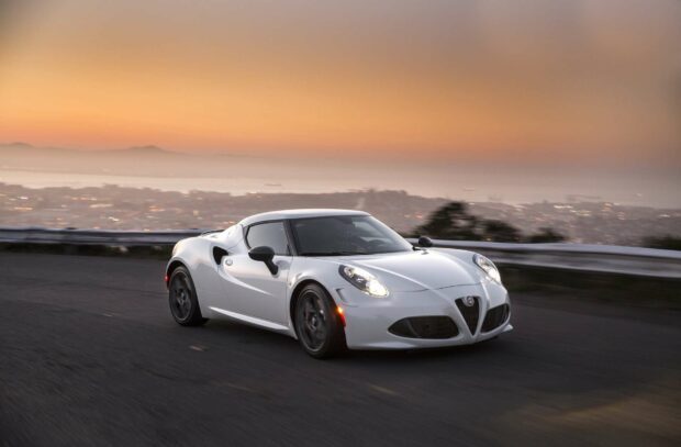 A white Alfa Romeo is driving on a road with a cityscape and mountains in the background during sunset, HD Desktop