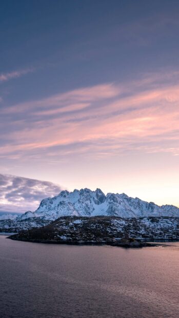 A snow covered Arctic mountain stands behind a rocky island during a peaceful sunset, 4K Phone Wallpaper
