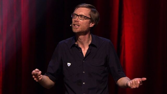 Stephen Merchant Performing Standup Comedy on Stage with Red Curtain Background Wallpapers