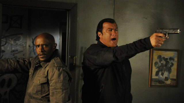 Steven Seagal Action Scene with Gun and Partner Intense Moment Wallpaper