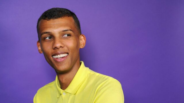 Stromae Portrait on Purple Background Bright Yellow Shirt Wallpaper