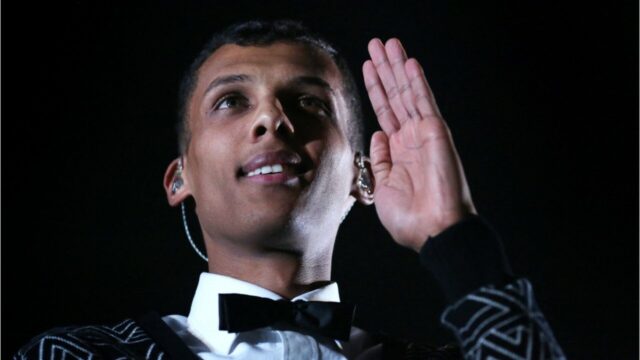 Stromae close up portrait with hand raised in stylish outfit for wallpapers
