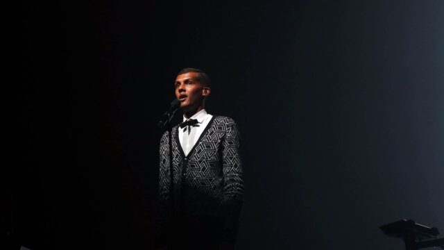 Stromae performing live in geometric patterned sweater Stromae wallpapers background