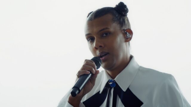 Stromae singing live in stylish white outfit perfect for Stromae wallpapers