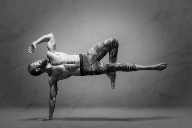 A muscular man performs a complex yoga pose balancing on one hand, HD Desktop Wallpaper