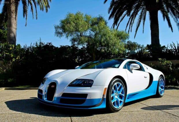 A white and blue Bugatti Veyron parked outdoors under the sun with green trees in the background, HD Desktop Wallpaper