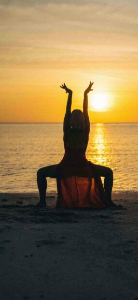 A person is practicing yoga in a seated pose facing the sunset over the ocean, enjoying peace and tranquility with yoga wallpapers, HD Phone Wallpaper
