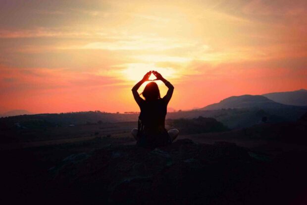 A person practices yoga with hands raised at sunset over a mountainous landscape, HD Desktop Wallpaper