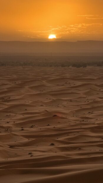 The Algeria Wallpapers showcase a stunning sunset sky above vast desert dunes with distant hills, 4K Mobile Wallpaper