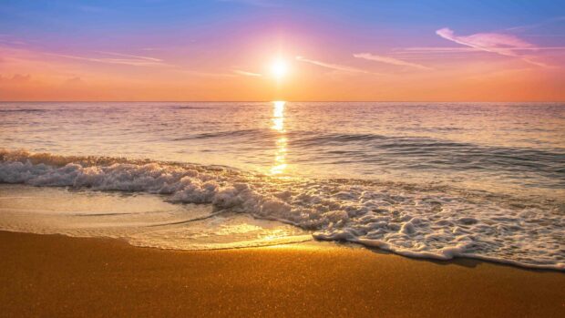 A serene sunset over the calm sea waves and sandy shore representing Dominica Wallpapers, 4K Desktop Wallpaper