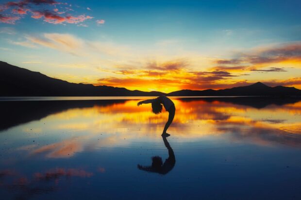 A person bending backwards beautifully reflecting on a calm lake with mountains in the background in Bolivia, HD Desktop Wallpaper