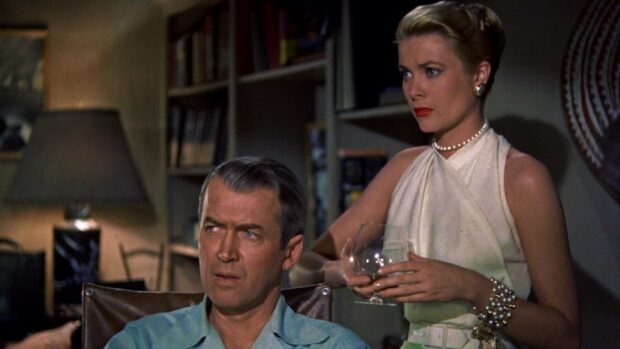 A man and a woman share a tense moment in a room with books and a lamp in an Alfred Hitchcock scene, HD Desktop Wallpaper