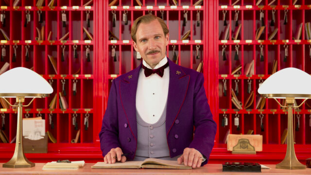 The Grand Budapest Hotel Concierge in Purple Uniform at Reception Desk Wallpaper