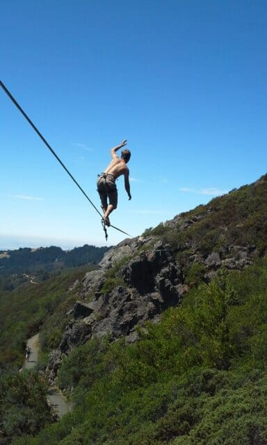 Thrilling Slacklining Adventure over Rocky Mountain Landscape under Clear Blue Sky