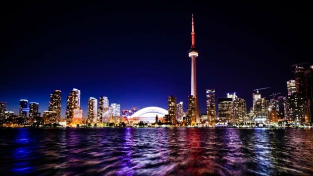 The CN Tower stands tall over Toronto with city lights reflecting in the water, 2K Desktop Wallpaper