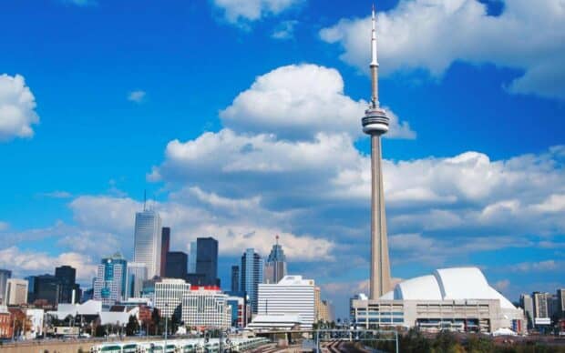 The CN Tower stands tall among Toronto buildings under a bright blue sky, HD Desktop Wallpaper
