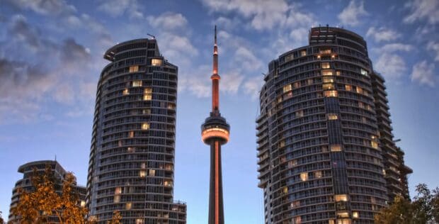 The CN Tower in Canada stands glowing between two modern high rise buildings at dusk, HD Desktop Wallpaper