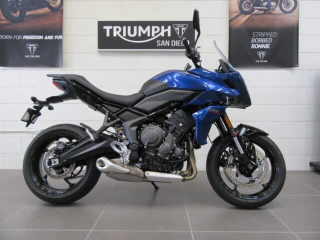 Triumph Tiger Sport 660 Blue Motorcycle Side View in Showroom Wall Background