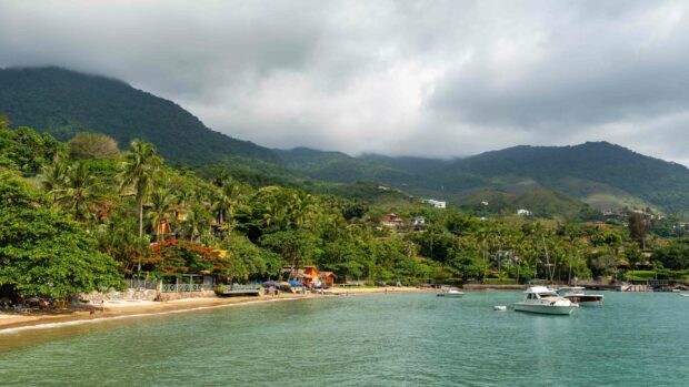 A tropical coast with boats anchored near lush green mountains in Dominica, 4K Desktop Wallpaper