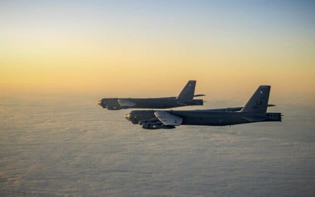 Two Boeing B 52 airplanes flying over a cloud covered landscape during sunset, 2K Desktop Wallpaper