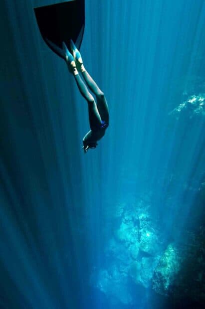 A freediver swims down into the deep blue ocean rock formations, HD Mobile Wallpaper
