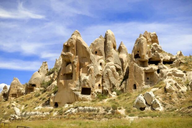 The ancient rock formations in Cappadocia have carved dwellings under a blue sky, HD Desktop Wallpaper