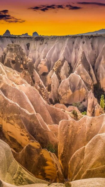 The Cappadocia region features unique rock formations under a golden sunset sky, HD Mobile Wallpaper