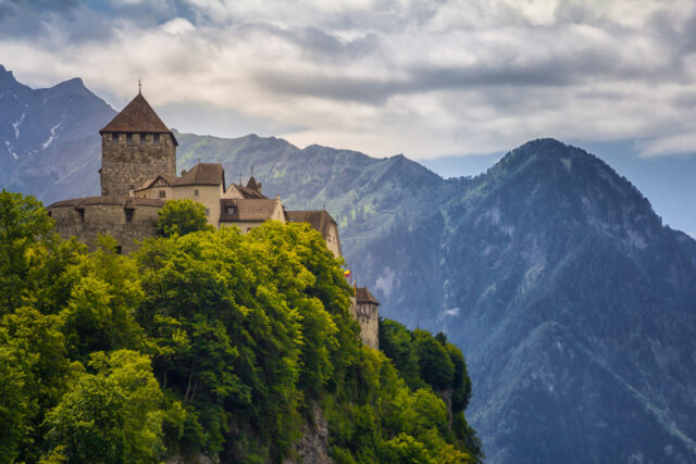 Vaduz Castle Nestled In Lush Greenery With Mountain Backdrop Wallpaper