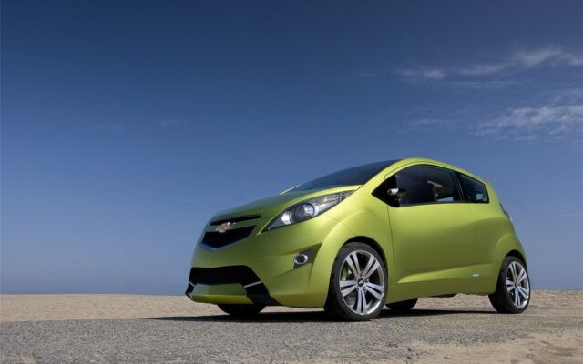 Vibrant Chevrolet Spark On Scenic Beach Road Wallpaper