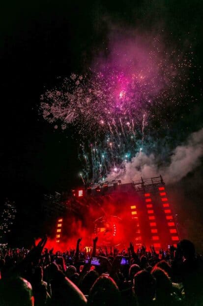 A vibrant concert crowd celebrates with colorful fireworks lighting up the night sky, HD Mobile Wallpaper