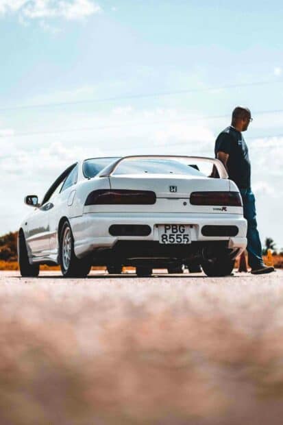 A white Honda Integra is parked on a road with a person standing next to it under a blue sky, HD Phone Wallpaper