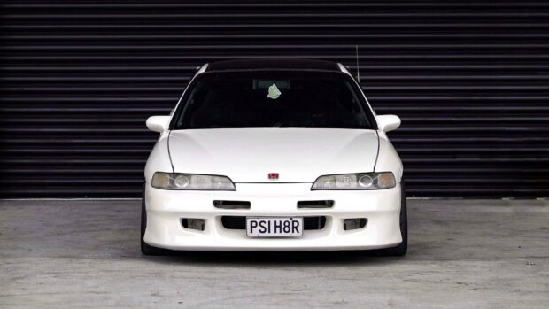 A white Honda Integra is parked in front of a black corrugated metal wall, 4K Desktop Wallpaper